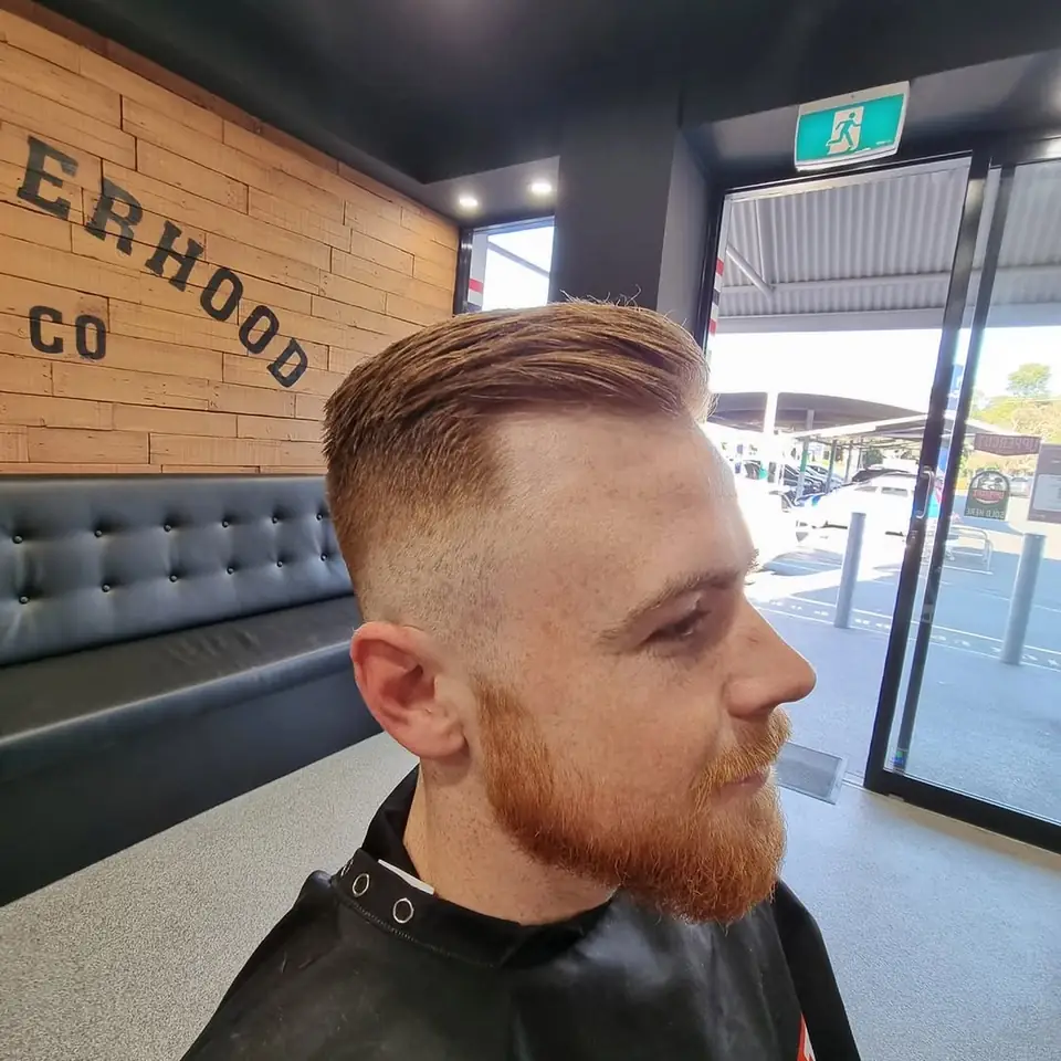 Beard shape-up and skin fade under the wall sign